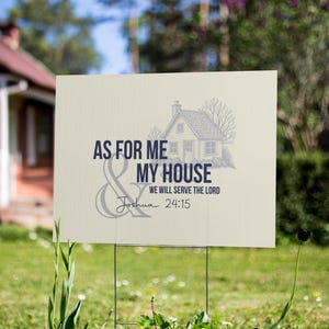 May include: Cream-colored yard sign with the text "AS FOR ME & MY HOUSE WE WILL SERVE THE LORD Joshua 24:15" in navy blue. A small house illustration is above the text. The sign is displayed outdoors on a metal frame.