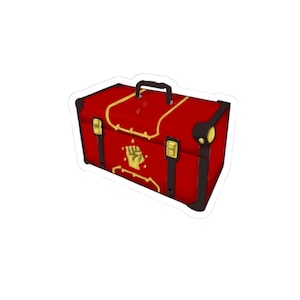 May include: A red rectangular storage chest featuring a black handle and corner reinforcements. The chest is decorated with gold-colored trim, two vertical black straps with gold buckles, and a central gold emblem of a clenched fist.