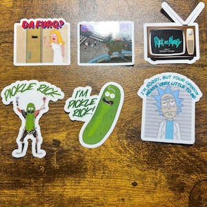 Può includere: Una collezione di adesivi colorati con personaggi e citazioni della serie animata "Rick and Morty". I disegni includono una TV, Pickle Rick e varie citazioni come "I'm Pickle Rick!" e "I'm sorry, but your opinion means very little to me."