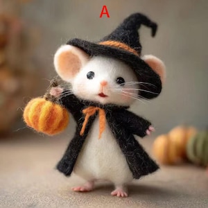 May include: A handcrafted Halloween mouse figurine, dressed in a black witch's hat and cape with an orange bow. The mouse holds a small orange pumpkin. The letter "A" is visible in the background.