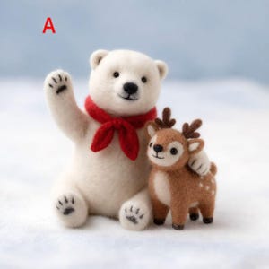 Puede incluir: Una figura de oso polar blanco de lana fieltrada con una bufanda roja alrededor del cuello, saludando con una pata. Junto al oso hay una pequeña figura de ciervo marrón con manchas blancas en el lomo y astas. La letra A aparece arriba a la izquierda.
