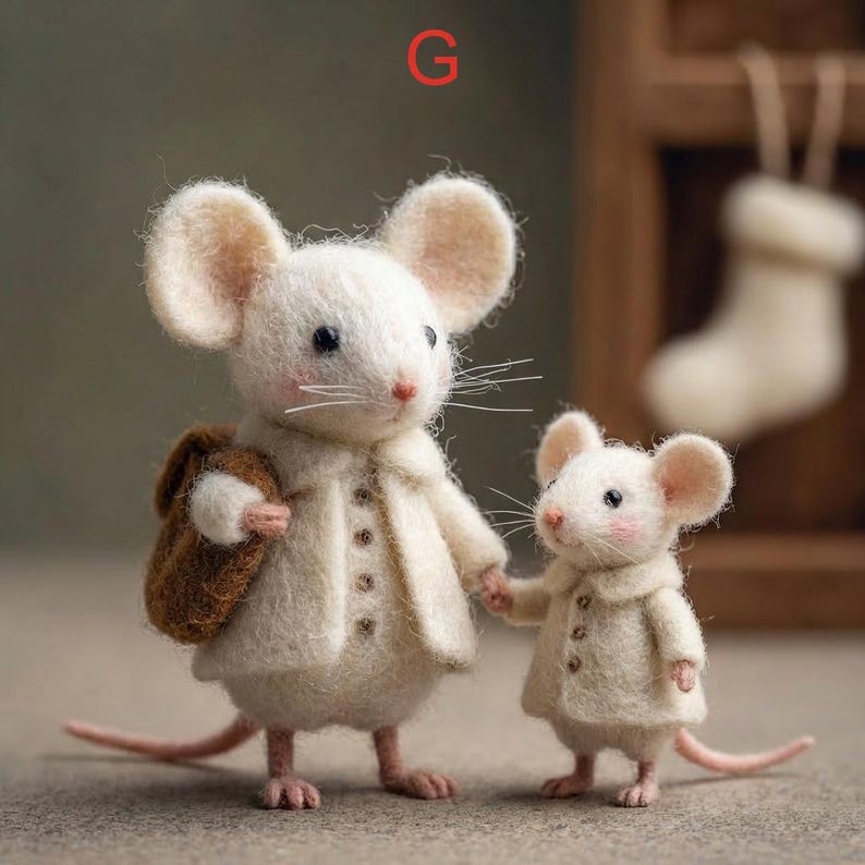 Peut inclure: Deux souris blanches en feutre, une grande et une petite, se tiennent c&ocirc;te &agrave; c&ocirc;te. La grande souris porte un manteau cr&egrave;me et un sac &agrave; dos marron. La petite souris porte un manteau assorti et tient la main de la grande souris. Les deux ont des oreilles et des nez roses.
