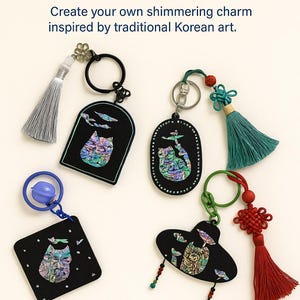 May include: A collection of Korean Mother-of-Pearl DIY keychain kits. The keychains feature black shapes with iridescent inlays and decorative tassels in various colors. Text on the image reads, "Korean Mother-of-Pearl DIY Keychain Kit" and "Create your own shimmering charm inspired by traditional Korean art."