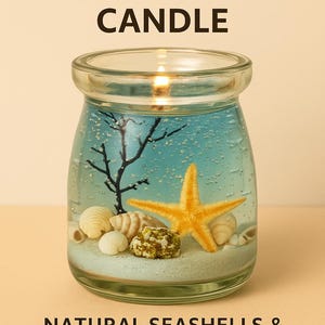 Puede incluir: Vela inspirada en el océano con conchas marinas naturales y una estrella de mar en el interior. La vela está en un frasco de vidrio transparente con un interior de gel azul, una mecha encendida y el texto "Handmade in Jeju Island".