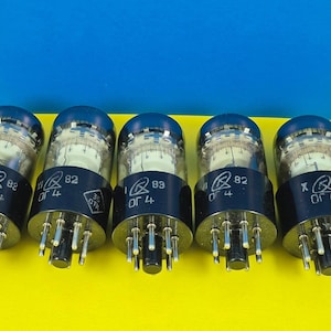 May include: Five vacuum tubes with clear glass bulbs and dark blue tops are arranged in a row. Each tube has a black base with multiple pins. The background is a split of yellow and blue.