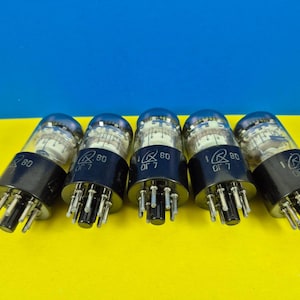 May include: Five vacuum tubes with clear glass bulbs and black bases are arranged in a row. Each tube has a silver interior and a black base with multiple pins. The tubes are labeled with the number "80" and other markings.