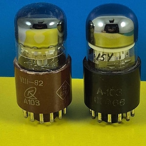 May include: Two vintage vacuum tubes with glass bulbs and brown and black bases. The tube on the left has the text "VIII-82", "A103", and a logo. The tube on the right has the text "15Y", "A-103", and "066". The background is blue and yellow.