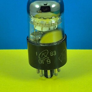 May include: A vintage vacuum tube with a clear glass bulb and a black base. The tube has internal components visible through the glass and a series of pins at the bottom. The base has printed text and numbers.