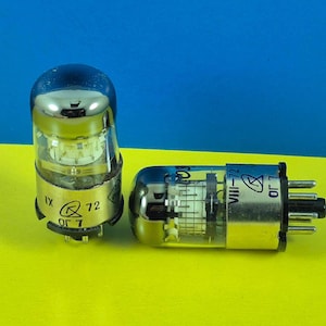 May include: Two vintage vacuum tubes with silver and clear glass components. One tube stands upright, while the other lies on its side. Both have black bases with pins and text that reads "IX", "72", and "VIII-72". The background is yellow and blue.