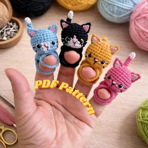 May include: A trio of cream-glazed ceramic mugs with a speckled finish. Each mug is adorned with a hand-painted design: a blue and green leaf, a yellow flower, and a red berry. The mugs have a minimalist aesthetic.