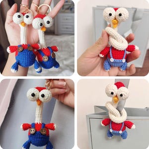 Puede incluir: Llavero de ganchillo con un diseño de pájaro caprichoso. El pájaro tiene una cabeza blanca con ojos grandes, una gorra roja y un pico amarillo. Lleva un peto azul con botones de madera y brazos rojos. El llavero está unido a un anillo dorado.