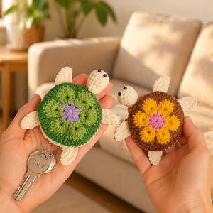 Può includere: Due portachiavi a forma di tartaruga fatti a mano all'uncinetto. Uno ha un guscio verde con un centro viola, e l'altro ha un guscio marrone con un centro giallo e rosa. Entrambi hanno pinne e teste bianche.
