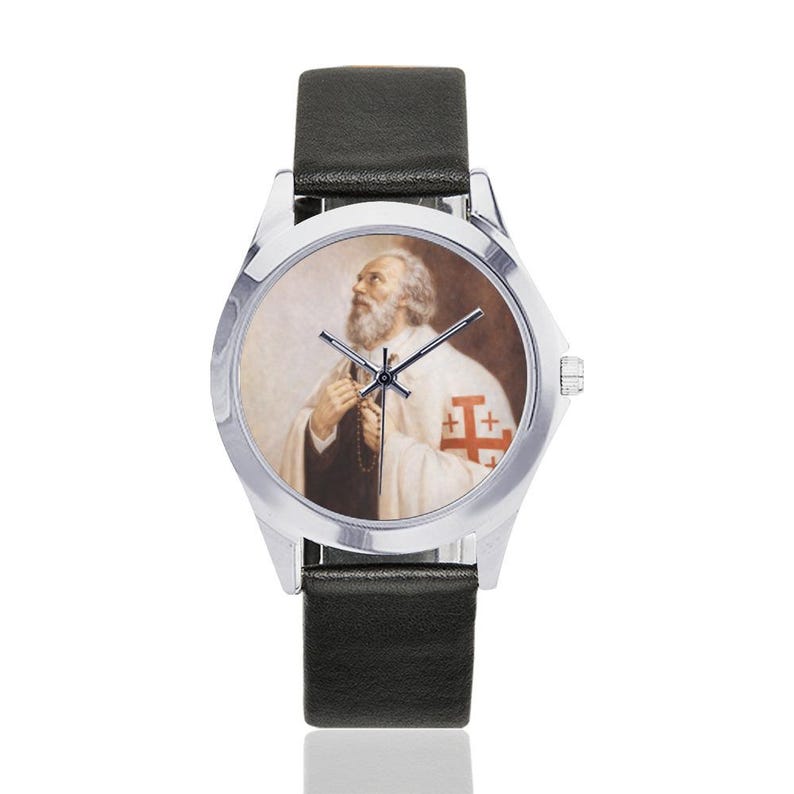 May include: A silver wristwatch with a black leather band. The watch face features a portrait of a man with a white beard and a white robe with a red cross emblem. The watch has silver hands and a silver bezel.