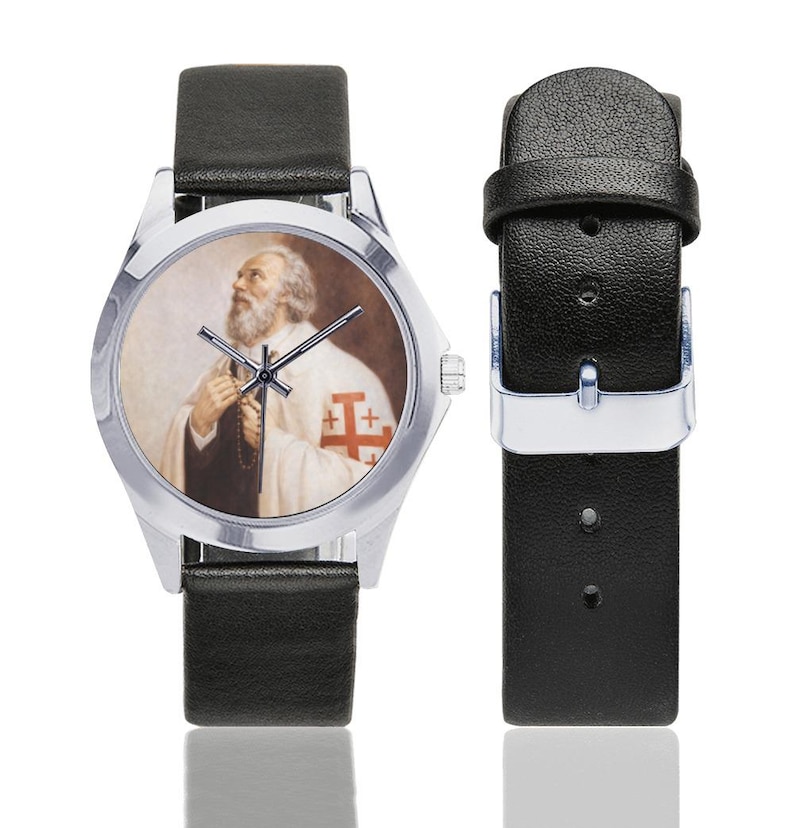 May include: A silver wristwatch with a black leather band. The watch face features a portrait of a man in religious attire. The man has a white beard and is wearing a white robe with a red cross emblem. The watch band is detached.