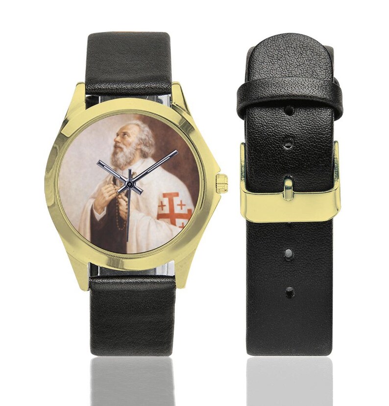 May include: Gold-tone wristwatch with a black leather band. The watch face features a portrait of a man in religious attire. The watch has a gold-colored bezel and black hands. The watch band is black leather.