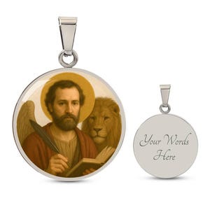 Può includere: Un ciondolo rotondo color argento con un'immagine religiosa di un uomo con un'aureola, che tiene una penna e un libro, con un leone dietro di lui. Il ciondolo ha un anello per una catena. Viene mostrato anche un secondo ciondolo vuoto.