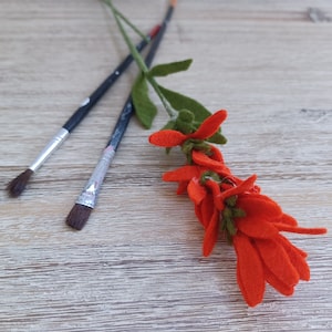 May include: Two black paintbrushes with silver metal ferrules and red felt flower stems with orange felt flower petals.