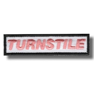 May include: Embroidered patch with the word "TURNSTILE" in pink thread on a white background. The patch has a black border and a rectangular shape. The patch is likely for clothing or accessories.