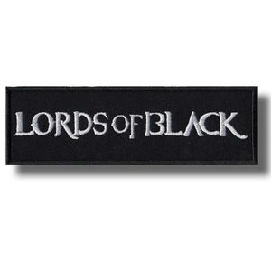 Op de afbeelding: Zwart rechthoekig embleem met de geborduurde tekst "LORDS OF BLACK" in wit. De patch heeft een zwarte rand en een schaduweffect, wat een verhoogd ontwerp suggereert. De tekst is in een vetgedrukte, schreefloze lettertype.