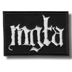 Pode incluir: Patch retangular preto com a palavra "mnta" bordada em branco em uma fonte gótica. O patch tem uma borda preta e é para roupas ou acessórios.
