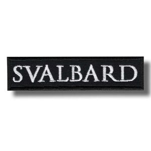 May include: A black rectangular patch with the word "SVALBARD" embroidered in white capital letters. The patch has a black border and is set against a white background.
