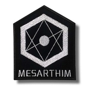 May include: Black and white embroidered patch with a geometric design. The patch features a white hexagon with a star-like pattern inside, and a white circle in the centre. The word "MESARTHIM" is embroidered in white at the bottom.