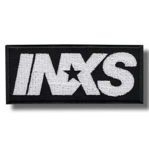 Könnte beinhalten: Ein rechteckiger schwarzer Aufnäher mit dem weiß gestickten Text "INXS" und einem Stern. Der Aufnäher ist ein Musikartikel, wahrscheinlich für Kleidung oder Accessoires. Das Design ist einfach und kühn, mit einer klaren Schrift.