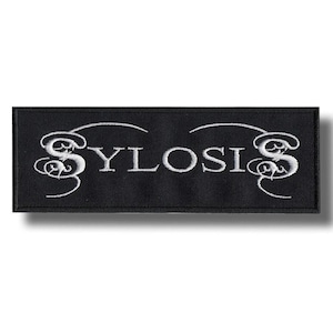 May include: Black rectangular patch with the word "SYLOSIS" embroidered in white, featuring decorative flourishes. This patch is likely designed for application on clothing or accessories.
