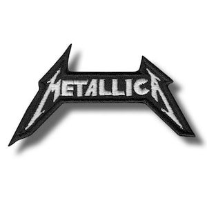 Może przedstawiać: Czarna i biała naszywka z haftem z napisem "METALLICA" w białych, dużych literach. Naszywka ma charakterystyczny kształt logo z ostrymi, kanciastymi punktami po każdej stronie i prawdopodobnie jest przeznaczona na kurtkę lub torbę.