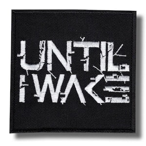 May include: A square black patch featuring white embroidered text: "UNTIL I WAKE". The lettering has a distressed, textured effect. The patch is bordered in black and is likely designed to be ironed on or sewn onto fabric.