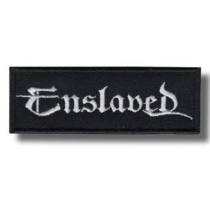 May include: A black rectangular patch with the word "Enslaved" embroidered in white gothic lettering. The patch has a clean, minimalist design, suitable for jackets, bags, or other apparel.