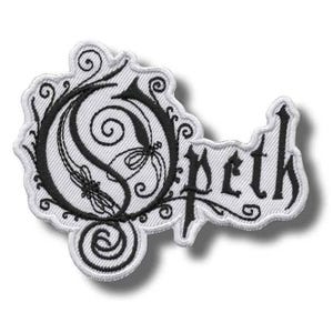 May include: Embroidered patch featuring the band name "Opeth" in a stylized black font on a white background. The patch has a unique shape with decorative swirls and a detailed design. The patch is likely for clothing or accessories.