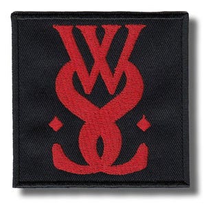 May include: Square black patch with a red stylized monogram design. The monogram appears to be two intertwined letters, possibly "W" and "S", with a diamond shape on each side. The patch has a stitched border.