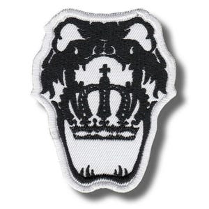 Puede incluir: Parche bordado en blanco y negro con un diseño de corona. El parche tiene un fondo blanco con un contorno negro y una corona negra detallada en el centro. Adecuado para ropa o accesorios.
