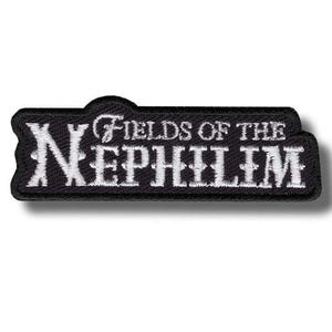 Puede incluir: Un parche bordado en blanco y negro con el texto "Fields of the Nephilim". El parche tiene forma rectangular con la parte superior curvada. El texto está en una fuente estilizada.