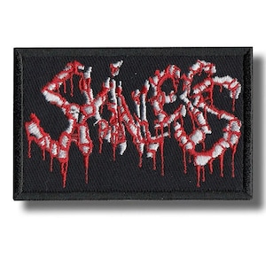 May include: Black rectangular patch with the word "SLAUGHTER" embroidered in white and red. The letters have a dripping blood effect. The patch has a black border and is likely for clothing or accessories.