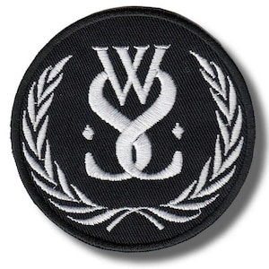 Puede incluir: Parche bordado redondo negro con un diseño blanco entrelazado de las letras "W" y "S", rodeado por una corona de laurel estilizada. El parche tiene una superficie texturizada y es para coser o planchar.