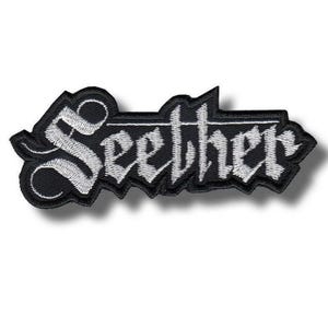 Könnte beinhalten: Ein schwarz-weißer, gestickter Aufnäher mit dem Wort "Seether" in einer gotischen Schriftart. Der Aufnäher hat einen schwarzen Hintergrund mit weißen Nähten, und der Text ist leicht gebogen. Er ist für Kleidung oder Accessoires bestimmt.