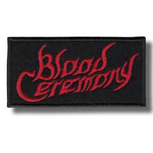 Puede incluir: Parche rectangular negro con las palabras "Blood Ceremony" bordadas en rojo, con letras de estilo gótico. El parche tiene un borde negro y está diseñado para ser cosido en ropa o accesorios.