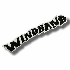 May include: A black and white patch with the word "WINDHAND" in a bold, stylized font. The text is black with a white border, set against a white background. The patch has a slightly irregular shape.