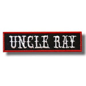 Può includere: Toppa ricamata con la scritta "UNCLE RAY" in bianco, con lettere stilizzate. La toppa ha uno sfondo nero con un bordo rosso. La toppa è di forma rettangolare.