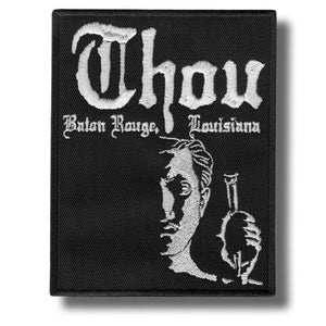 May include: Black embroidered patch featuring the word "Thou" in white gothic script. The text "Baton Rouge, Louisiana" is below. A white illustration of a person holding a bottle is shown.