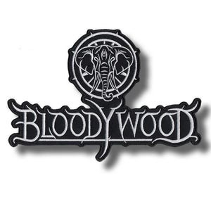 Könnte beinhalten: Schwarz-weißer, gestickter Aufnäher mit dem Text "BLOODYWOOD" in einer stilisierten Schriftart. Oberhalb des Textes befindet sich ein kreisförmiges Emblem mit einem Elefanten-Design. Der Aufnäher hat ein detailliertes, strukturiertes Aussehen.