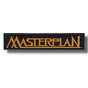 May include: A rectangular black patch with the word "MASTERPLAN" embroidered in gold thread. The patch has a clean, minimalist design, with the text centered and the edges neatly finished. The patch is likely designed to be sewn onto clothing or accessories.