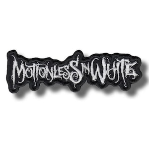 May include: A black and white embroidered patch featuring the band name "Motionless in White" in a stylized, gothic font. The patch has a black border and is designed for application on clothing or accessories.
