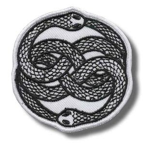 May include: Embroidered patch featuring a black and white design of two intertwined snakes forming a circular shape. The snakes are detailed with scales and have visible eyes. The patch has a white background and a white border.