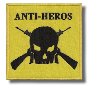 Könnte beinhalten: Gelber quadratischer Aufnäher mit dem Text "ANTI-HEROS" über einem schwarzen Totenkopf mit gekreuzten Gewehren. Der Aufnäher hat einen gelben Rand und ist wahrscheinlich ein gesticktes Design.