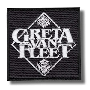Può includere: Una toppa quadrata nera con testo e design ricamati in bianco. Il testo recita "GRETA VAN FLEET" in un carattere stilizzato, racchiuso all'interno di una forma a diamante bianca. Elementi floreali decorativi in alto e in basso del diamante.