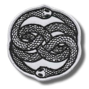 May include: A circular embroidered patch featuring a black and white design of two intertwined snakes forming a figure-eight shape. The snakes have detailed scales and are set against a white background with a white border.