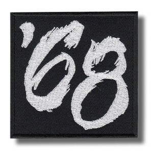 May include: Square black patch with white embroidered text reading "'68". The numbers are in a bold, cursive style. The patch has a black border and is likely an iron-on or sew-on patch for clothing or accessories.